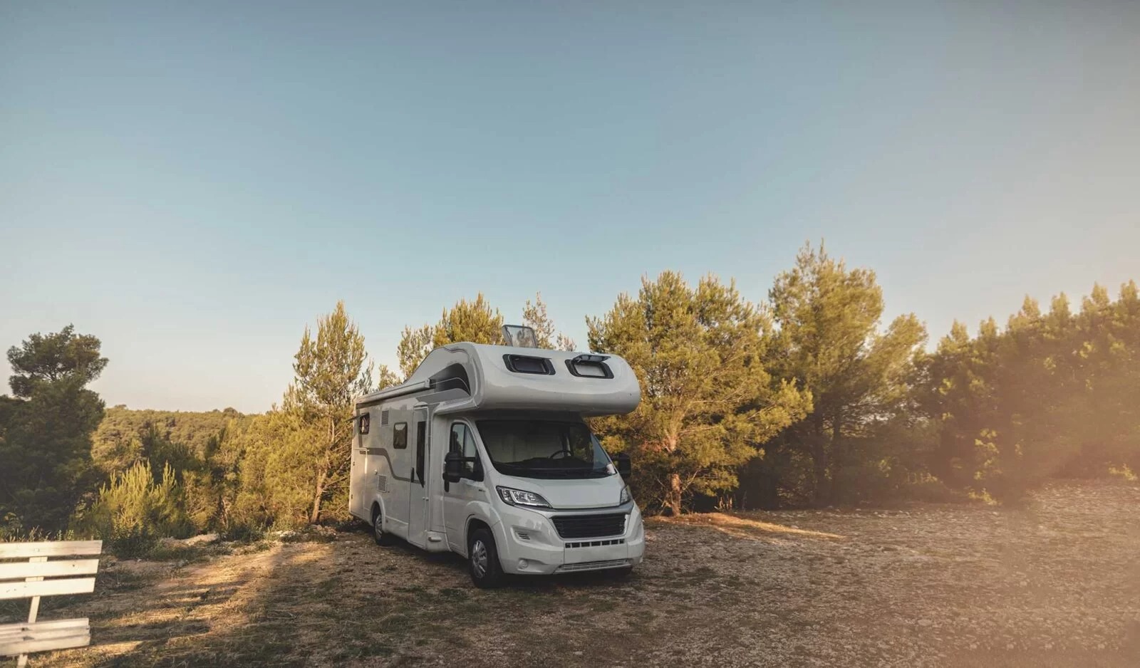 Camper a noleggio parcheggiato in un bosco al tramonto